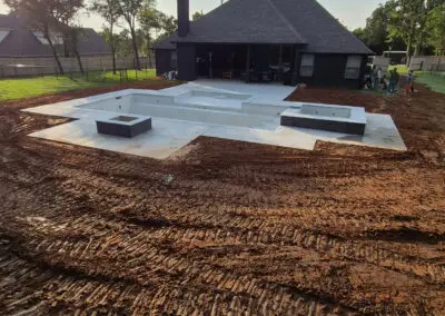 Modern backyard concrete pool shell under construction behind suburban house
