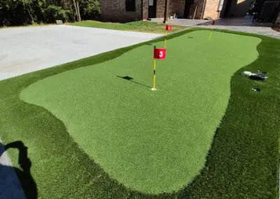 Backyard synthetic putting green with three numbered red flags