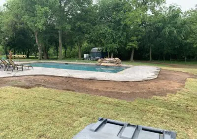 Residential backyard in-ground pool with rock waterfall and surrounding patio