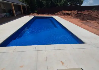 Rectangular backyard pool with bright blue water and concrete decking