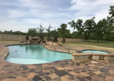 backyard freeform pool and raised spa with natural stone decking