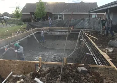Workers installing rebar and plumbing for a residential in-ground pool construction