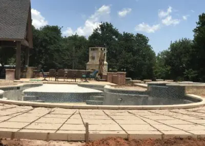 Backyard pool under construction with mosaic-tiled spa and patio furniture