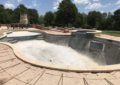 Backyard pool under construction with mosaic-tiled spa and patio furniture