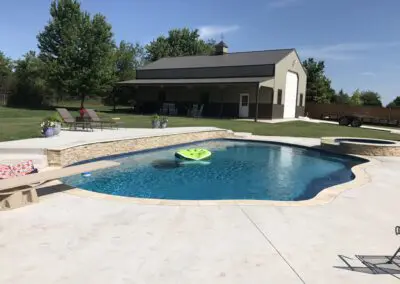 Residential backyard swimming pool with lounge chairs and detached garage