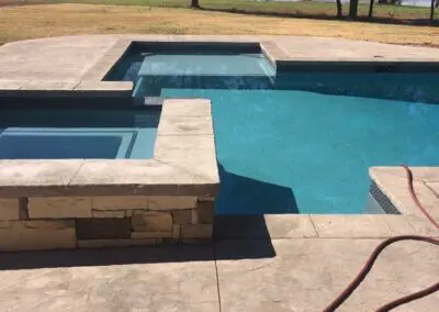 Modern backyard pool and spa with concrete deck and lake view