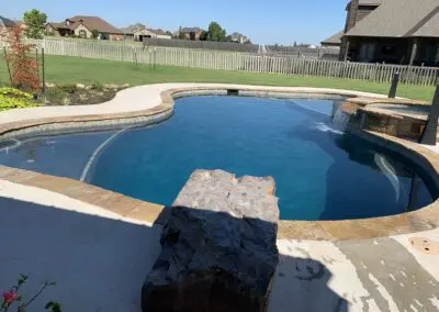 Backyard freeform pool with rock diving platform and spa waterfall