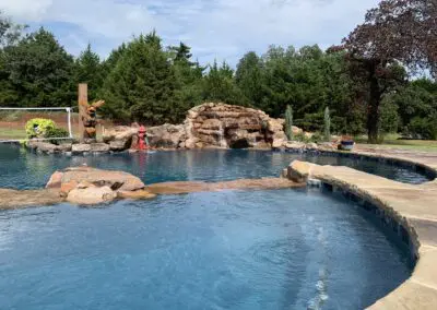 Backyard freeform pool with rock waterfall, tanning ledge, and landscaping