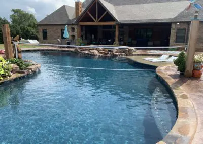 Backyard custom pool with tanning ledge, rock waterfall, and patio