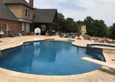 Backyard swimming pool with spa, diving board, lounge chairs, and brick patio