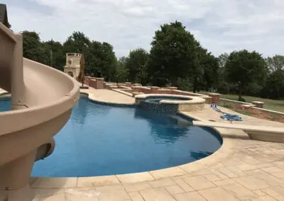 Backyard freeform pool with slide, spa, diving board, and patio