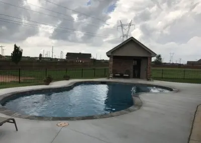 backyard freeform pool with cabana and cloudy sky
