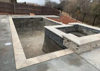Unfinished backyard concrete pool and raised spa with tiled coping