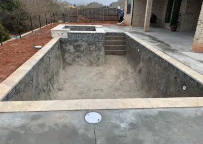 Unfinished concrete backyard pool and raised spa under construction