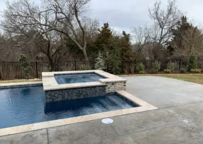 Backyard modern pool with raised spa and travertine coping