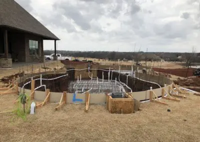 Residential backyard pool construction site with rebar, formwork, and plumbing