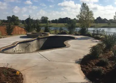 Empty backyard concrete pool shell under construction with stone coping