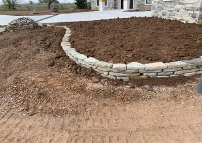 stone garden bed border with freshly turned soil in front of house