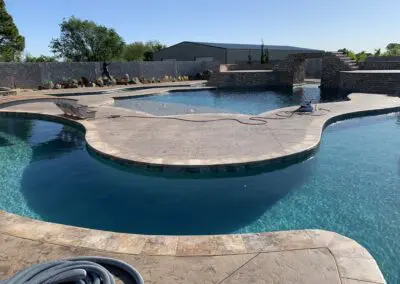 Custom luxury backyard pool with tanning ledge, waterfall and stone coping