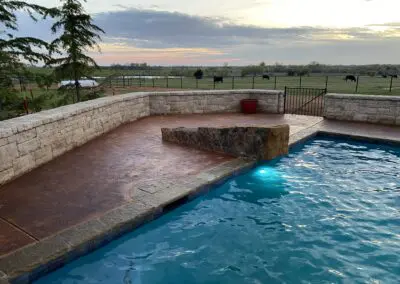 Pool at dusk with lit underwater light, stone deck and countryside view