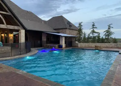 Evening backyard pool with blue LED lights and covered patio