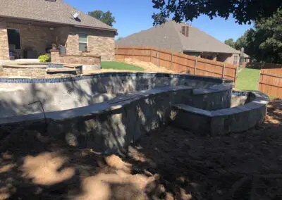 Backyard partially constructed stone swimming pool and raised spa under construction