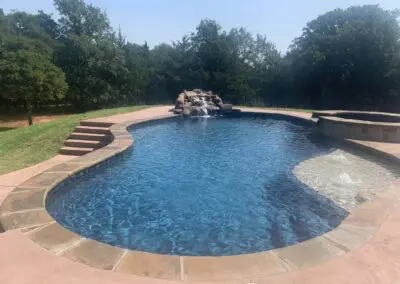 Backyard freeform pool with rock waterfall, tanning shelf, and spa steps