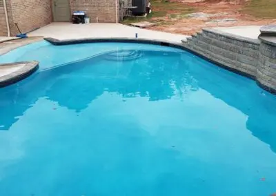 Residential in-ground blue swimming pool with raised spa and stone retaining wall
