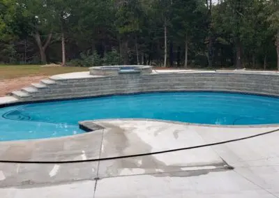 Residential in-ground freeform swimming pool with raised spa and concrete deck