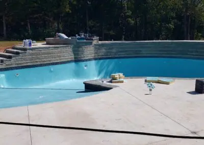Empty in-ground pool under construction with surrounding concrete patio