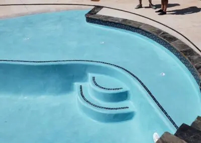 Curved newly plastered pool with submerged steps and stone coping