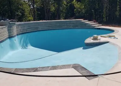 Completed in-ground pool shell with steps, spa ledge, and surrounding deck