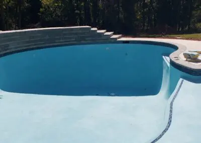empty backyard swimming pool under renovation with stacked stone retaining wall