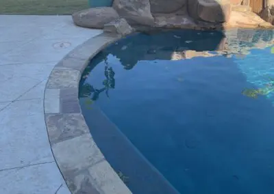 Residential pool with curved stone coping and rock waterfall feature