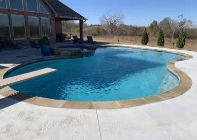 Residential inground pool with diving board, spa waterfall, and patio