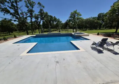 Modern rectangular backyard pool with concrete deck and lounge chairs