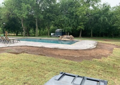Residential backyard in-ground pool with rock waterfall and surrounding patio