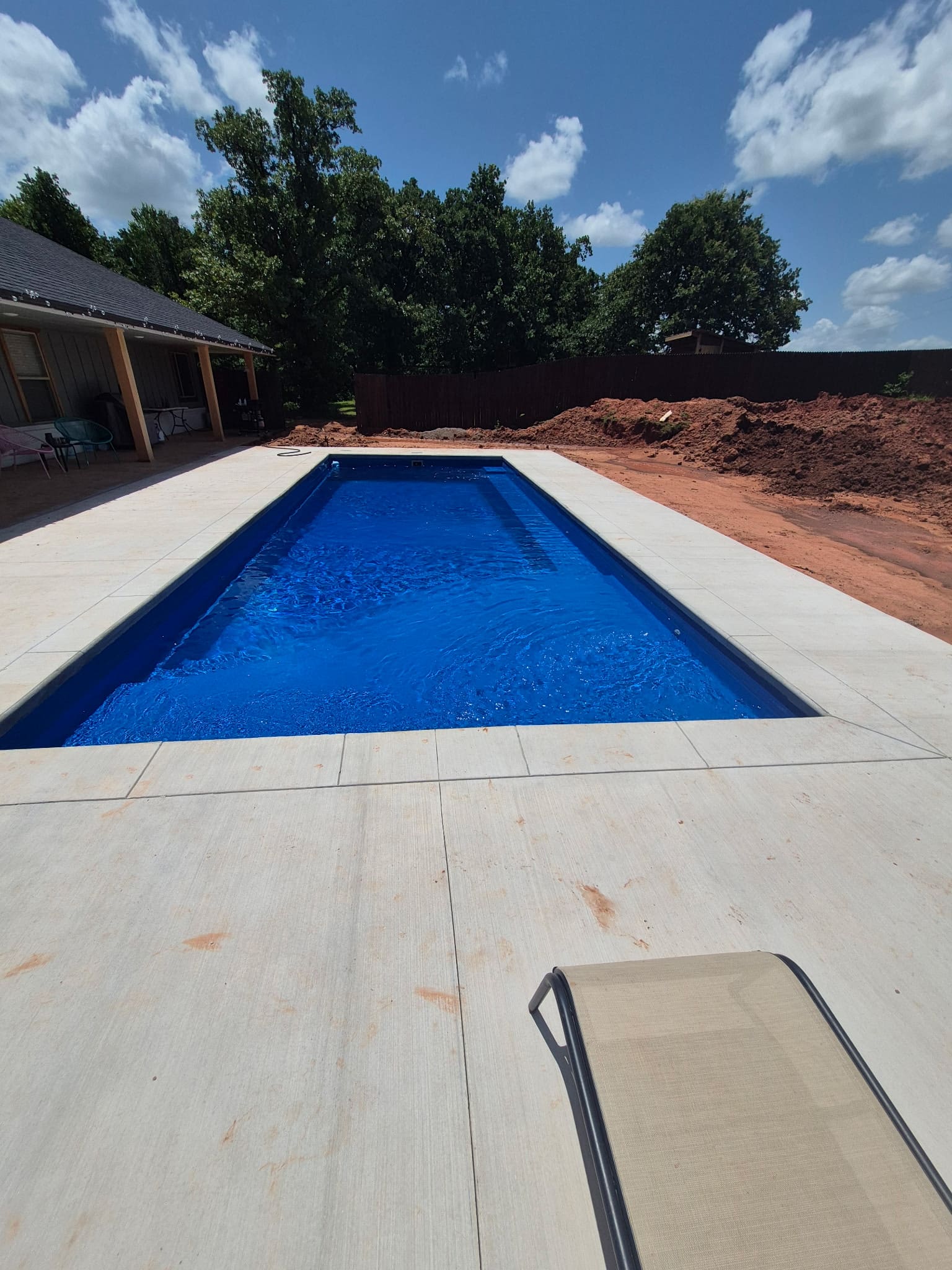Rectangular backyard gunite pool with bright blue water and concrete deck
