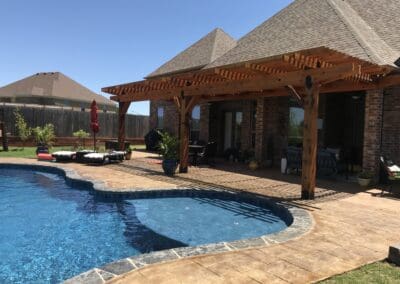 Backyard swimming pool with pergola-covered patio and lounge chairs