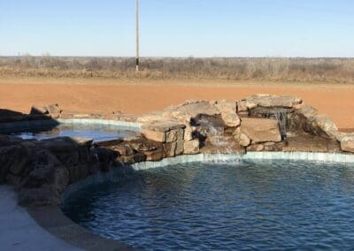 Backyard natural stone pool with tiered waterfall and clear blue water