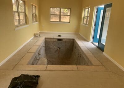 Indoor small plunge pool under renovation inside yellow room with blue door