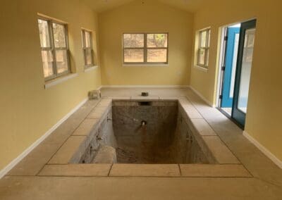 Indoor small plunge pool under renovation inside yellow room with blue door