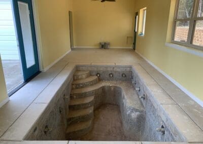 Indoor small plunge pool under renovation inside yellow room with blue door