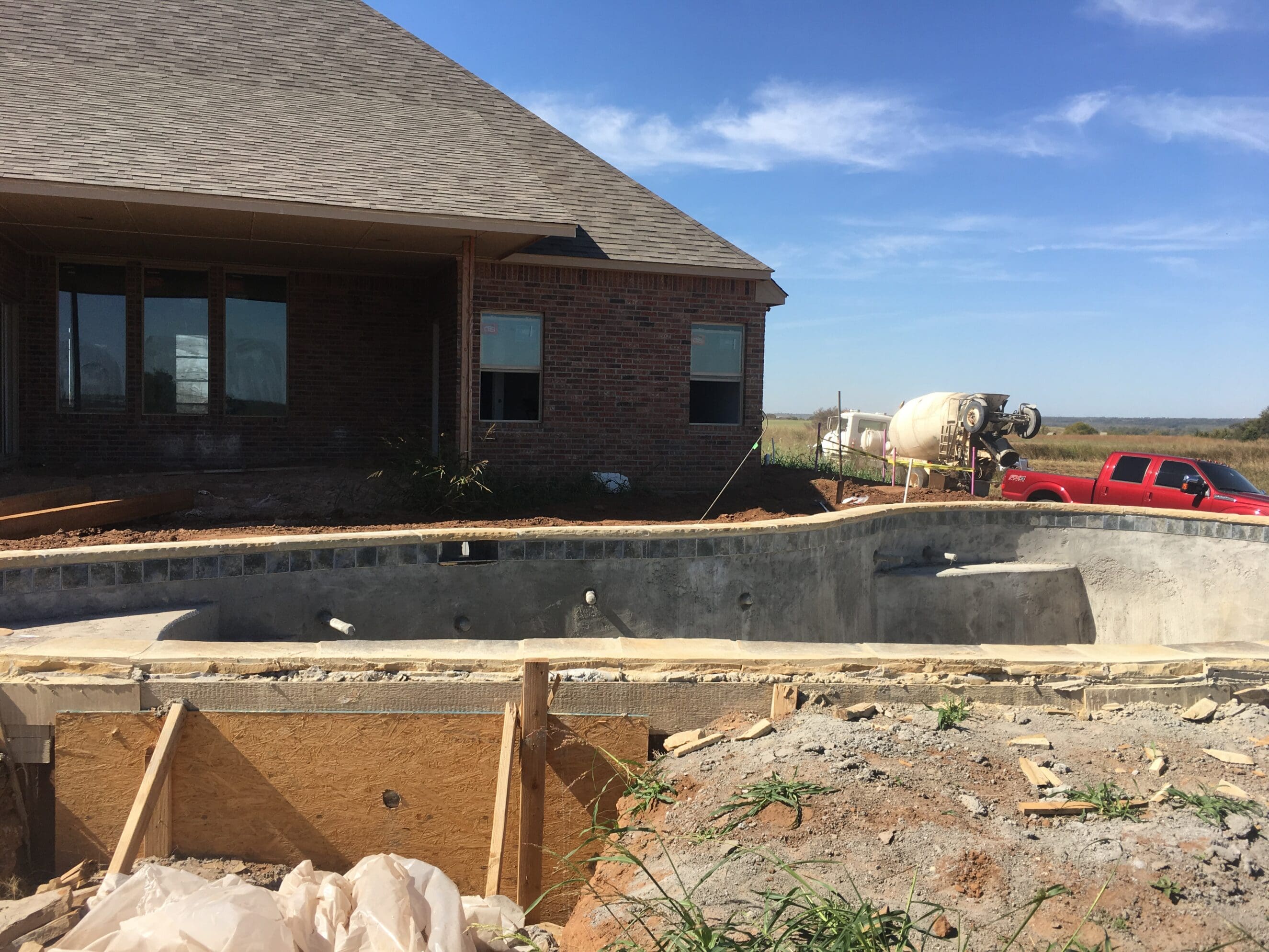 backyard gunite pool under construction beside new brick home