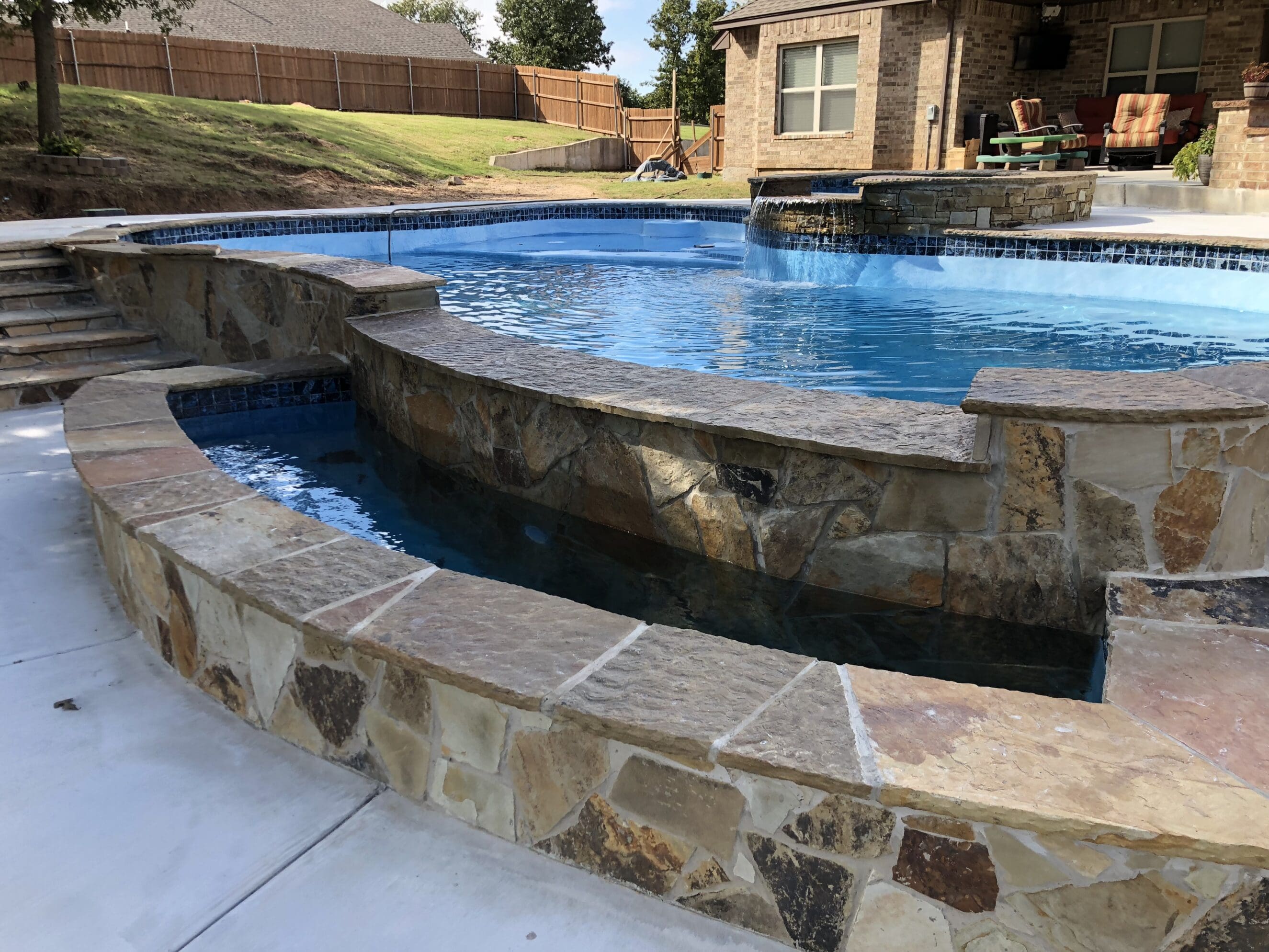 Backyard custom gunite pool with stone spa, waterfall, and patio