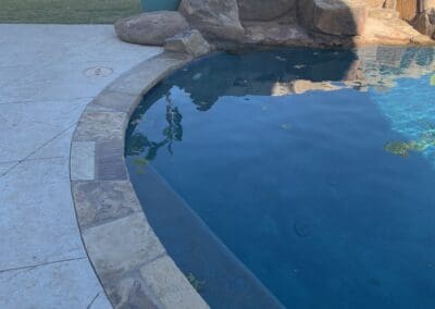 Residential pool with curved stone coping and rock waterfall feature